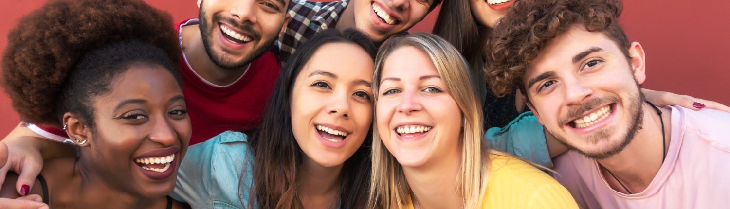 Group of seven smiling, happy individuals against a red background.